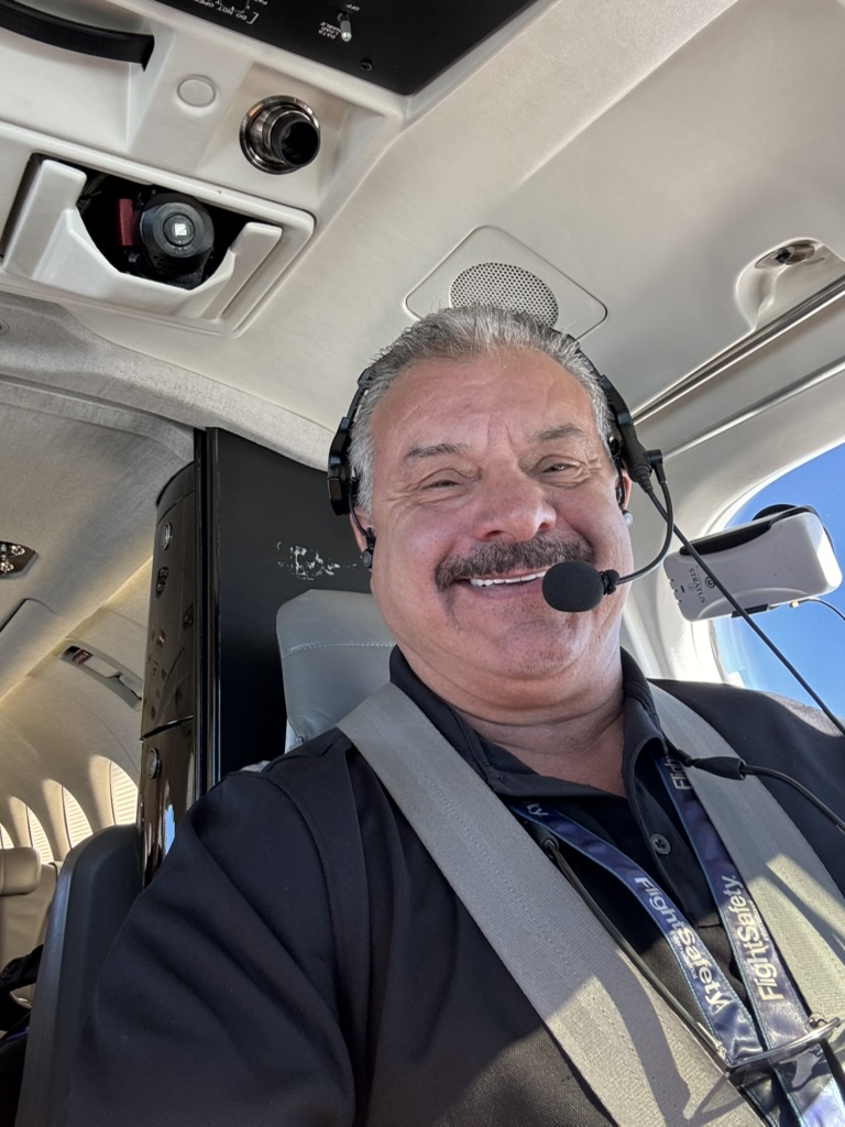 Captain Frank smiling in the cockpit with headset and harness