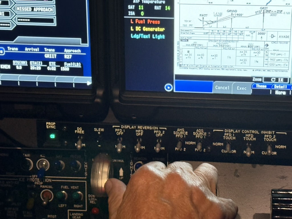 Captain Frank's hand on cockpit controls with approach chart displayed